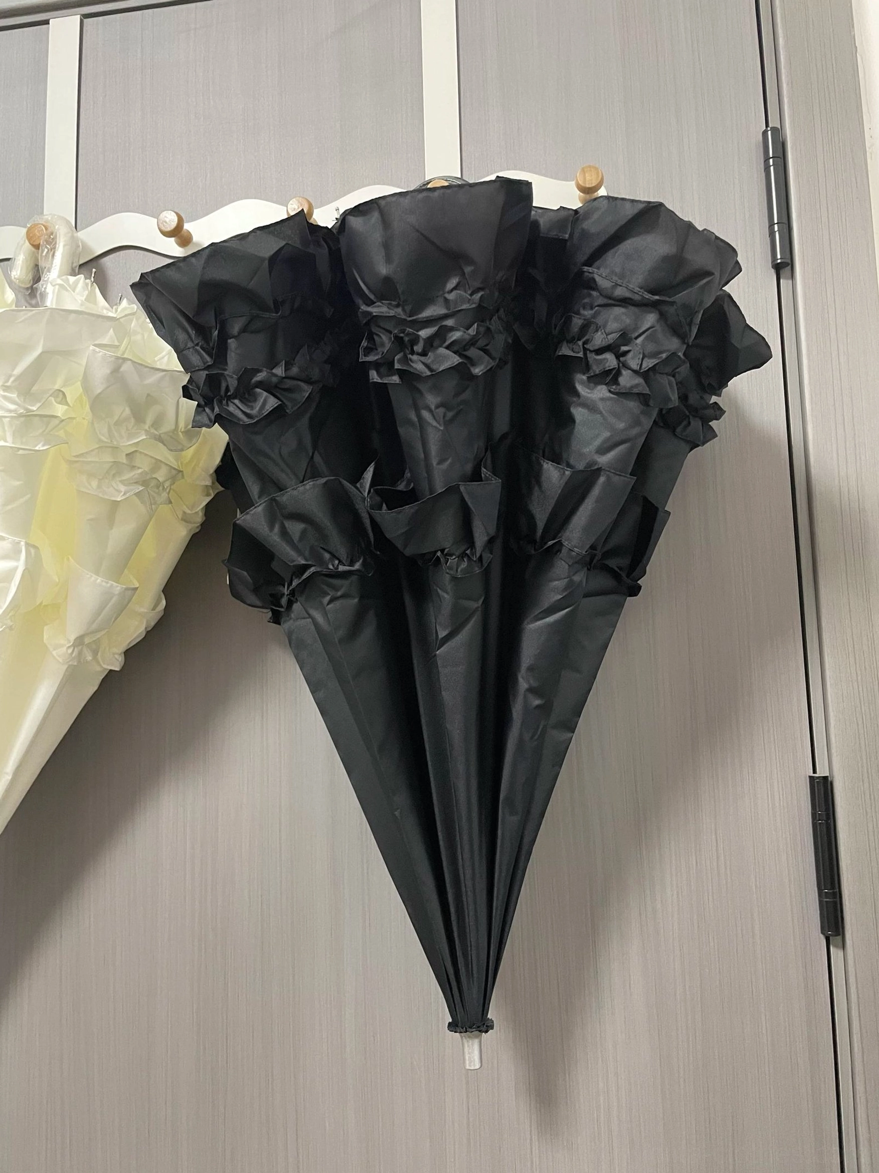Milky white multi-layer ruffled Lolita parasol with cascading dimensional frill trim creating dramatic silhouette, overhead flat lay demonstrating layered design complexity