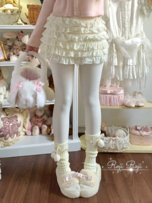 Milky white thickened velvet lolita winter pantyhose front view worn with ruffled mini skirt and fuzzy bow slippers in sweet lolita coordinate