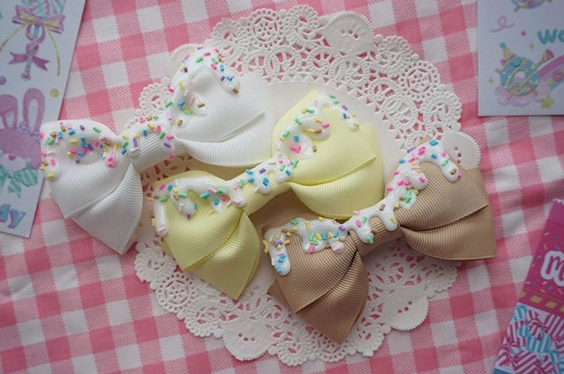 Mini cream cake themed sweet lolita bow hair clips in four colors with frosting decoration on lace background flat lay