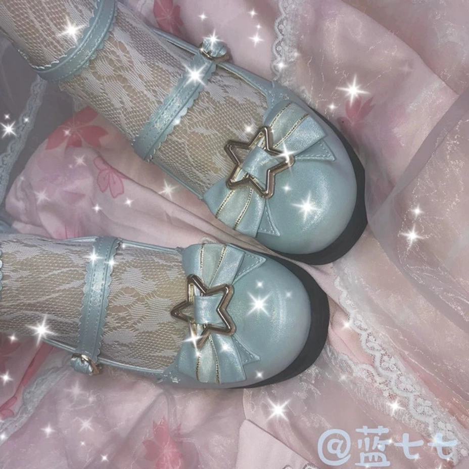 Close-up flat lay of mint blue sweet lolita mary jane shoes with iridescent shiny upper star gold ornament crisscross ruffled ankle straps worn on pink satin background
