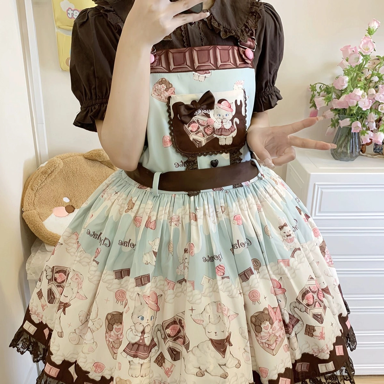 Model wearing mint green base Lolita salopette with brown puff sleeve blouse, belted waist, detailed chocolate cat chest print, half-body front close-up shot in bedroom with flower decor