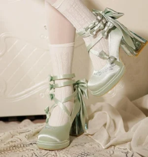 Mint green elegant Lolita transparent heel shoes worn on-foot with white knee-high stockings, showing side angle view with satin ribbon bows and floral embroidered toe cap details