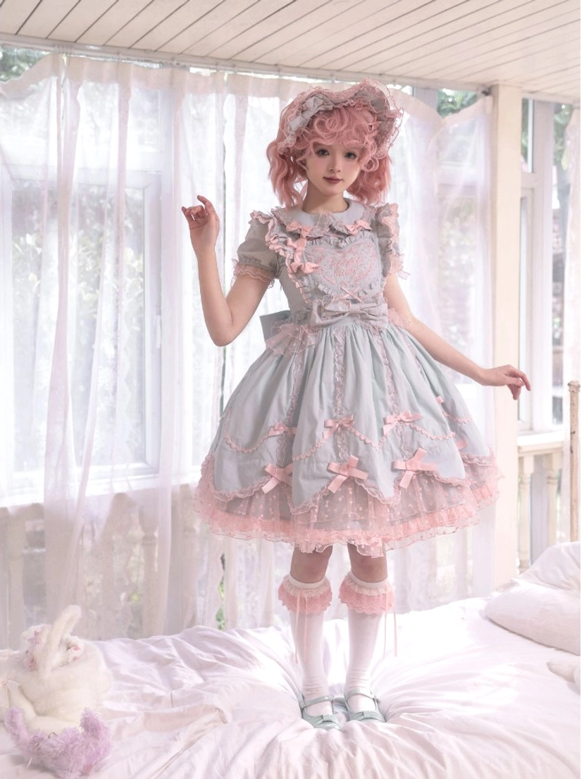 Mint green Lolita JSK dress with petal-shaped ruffled hem and pink lace trim on model with curly wig