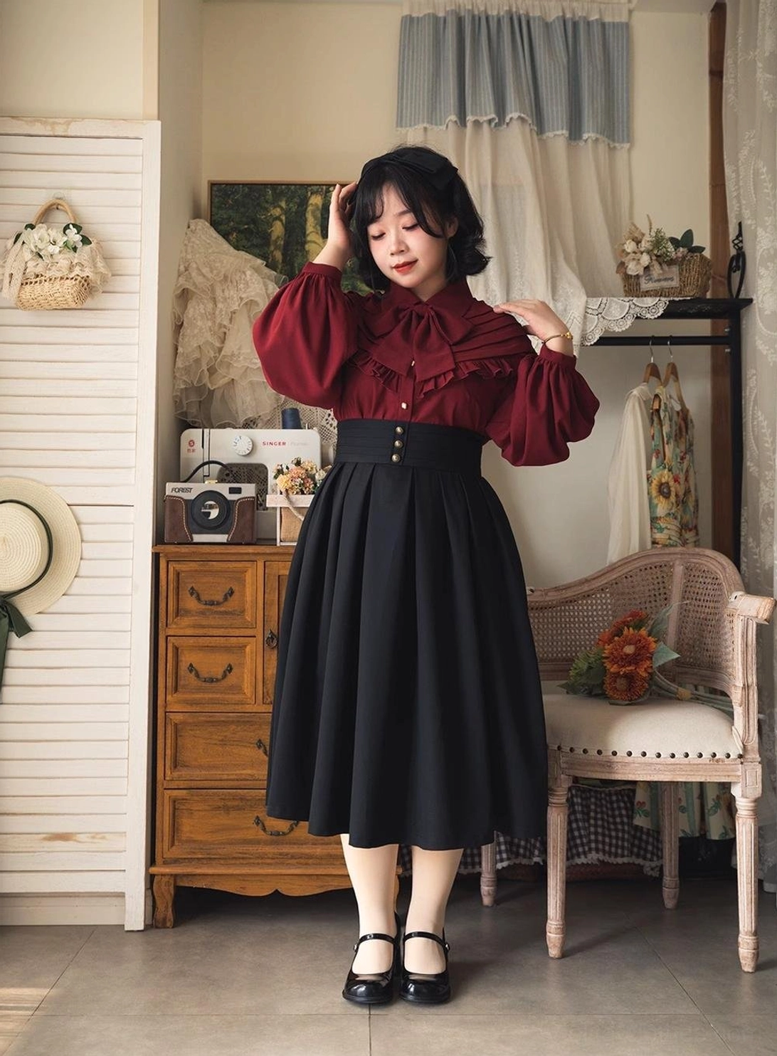 Model photographed from three-quarter side angle wearing burgundy Lolita blouse and black midi skirt, highlighting long puff sleeves, elegant vintage silhouette and high-waisted skirt proportion