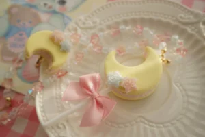 Handcrafted moon clay pendant and mini moon ornament set featuring pastel yellow resin with delicate beaded chain on vintage teddy bear postcard background