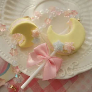 Celestial moon lollipop lolita necklace with iridescent pink star beads and pink satin bow on embossed white plate with gingham tablecloth backdrop