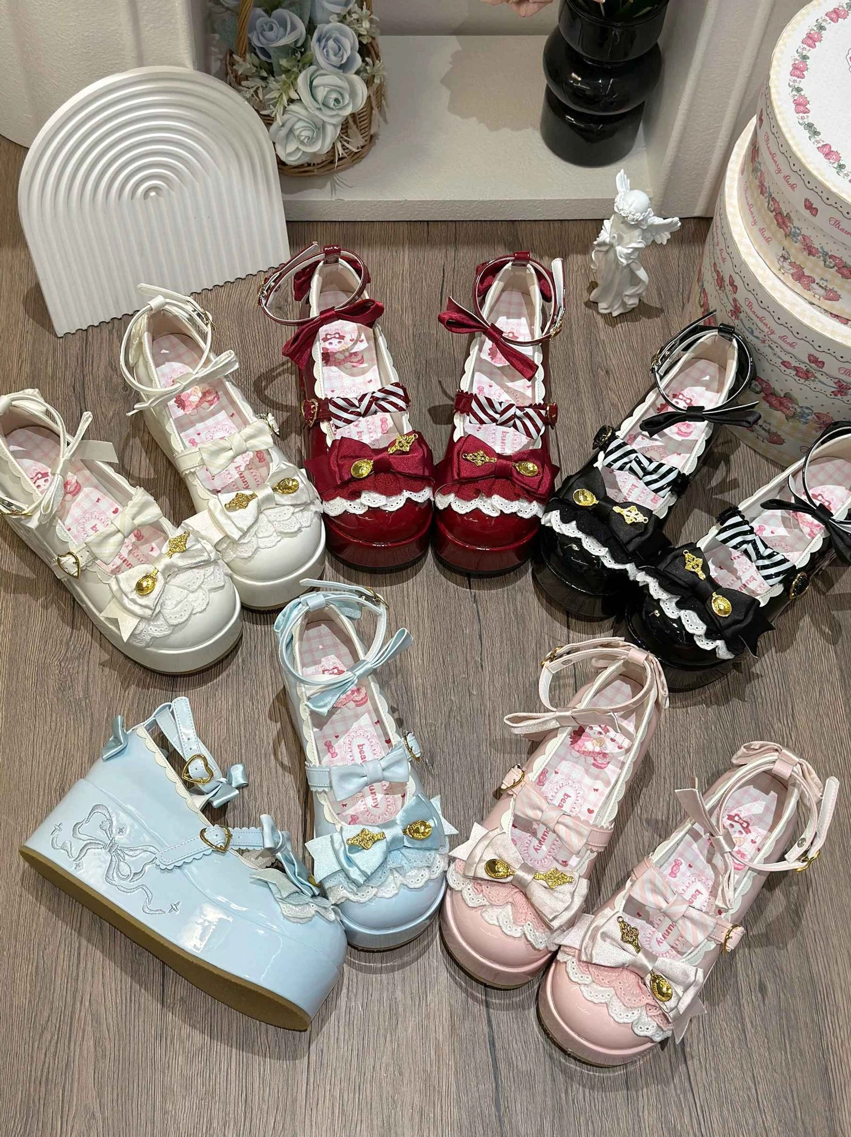 Assorted mousse roll platform sweet lolita shoes in multiple colorways displayed overhead on decorated table with bows and gold metal spoon accents