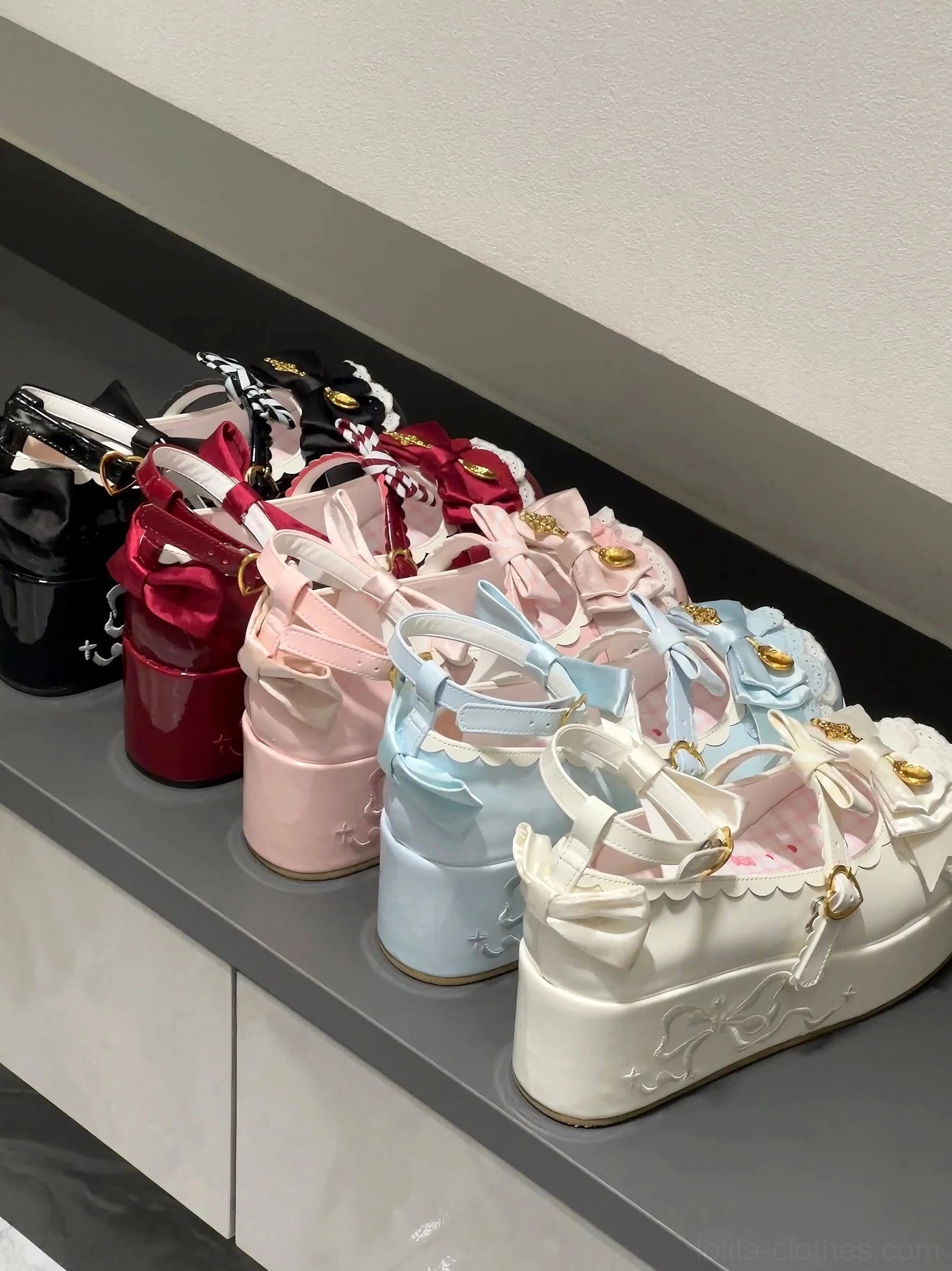 Row of mousse roll platform sweet lolita shoes arranged on cabinet shelf showing bow lace trim and substantial platform sole construction