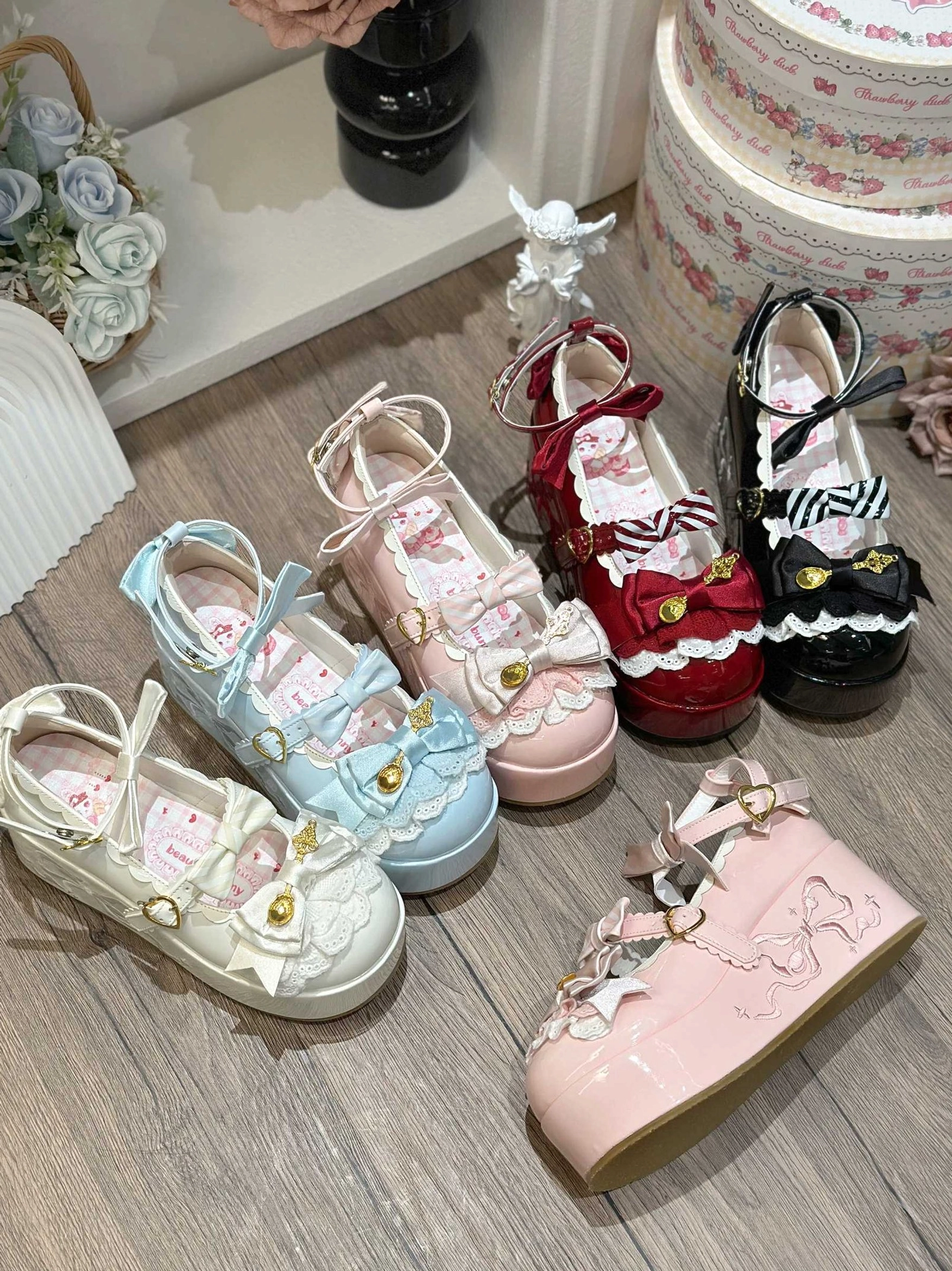 Multiple pairs of mousse roll sweet lolita platform shoes in light blue pink white wine red and black zebra stripe styles displayed on wooden table
