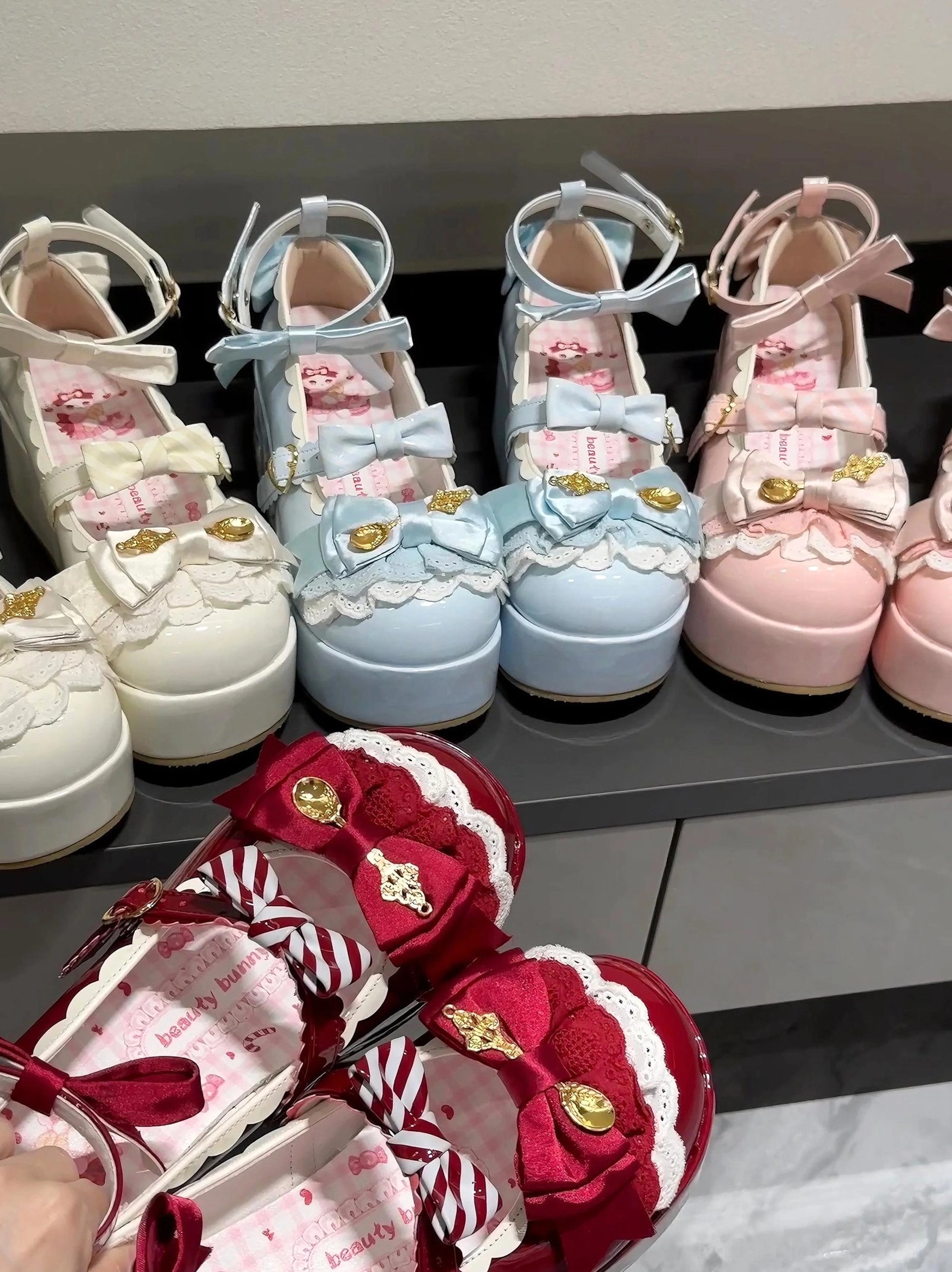 Four color options of mousse roll sweet lolita platform shoes with ankle strap bow decorations and gold metal buckles on marble counter
