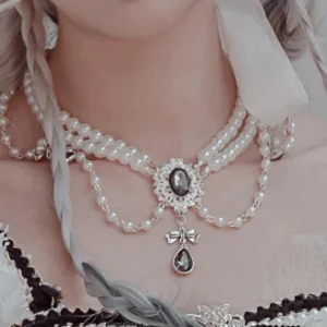 Multi-layered pearl bridal necklace featuring gemstone centerpieces, tassel chains, teardrop dark gem pendants, and decorative pearl strands displayed on model's neckline in close-up frontal view showing delicate jewelry layering