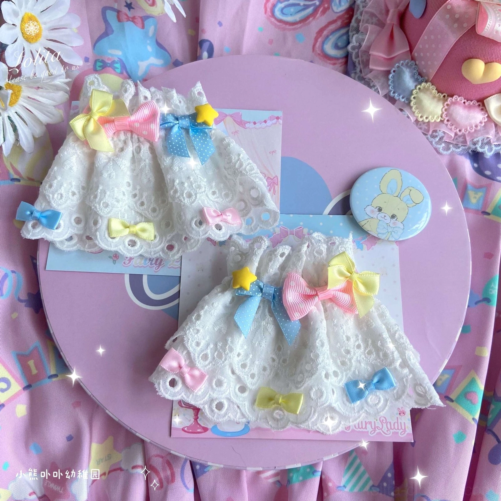 two pairs of pink yellow blue multicolor bow lace wrist cuffs with bunny badge on pink tray background