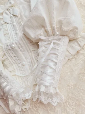Close-up detail of satin ribbon lace-up ruffled cuffs and pearl-embellished front placket showing ornate lace frills and quality construction on lolita blouse