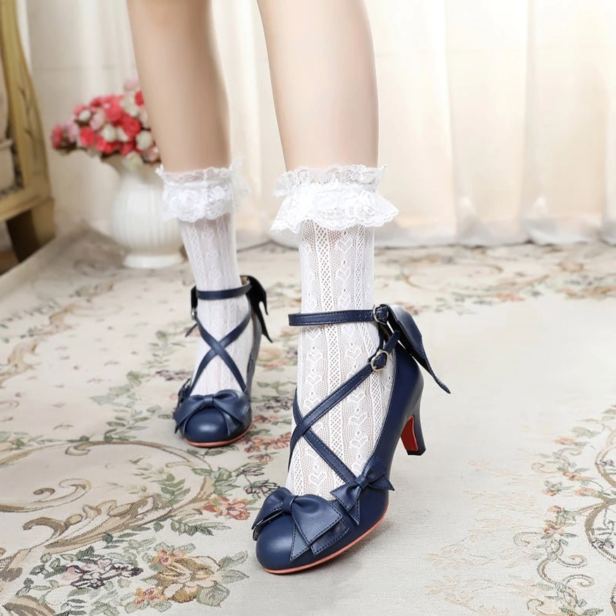 Navy blue cross-strap sweet Lolita Mary Jane heels shown from side-front view on vintage indoor shooting background with flower decor, featuring crisscross straps and red sole