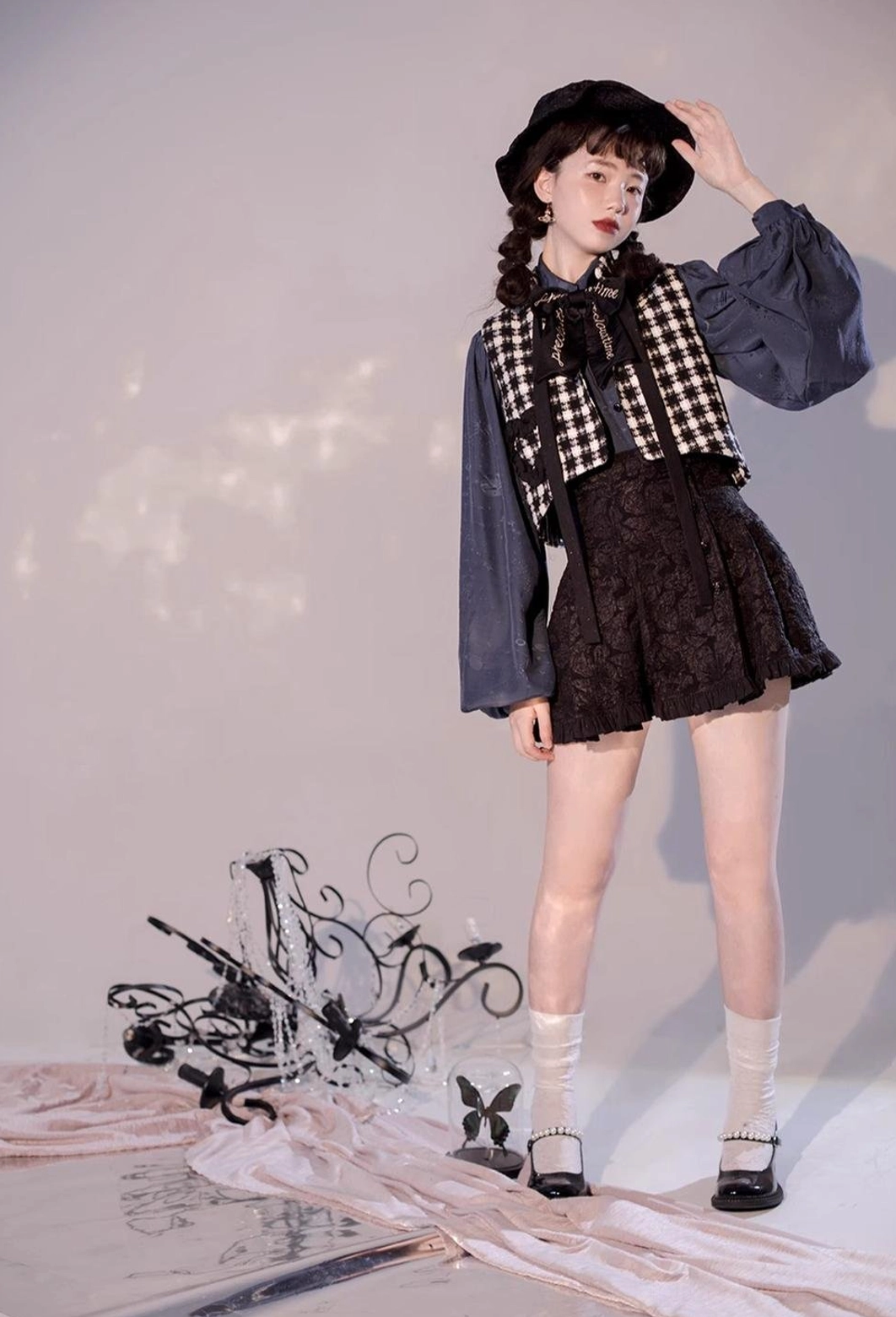 Layered retro Lolita outfit navy blue blouse full body front view model with houndstooth vest black mini skirt and vintage decorative prop studio scene