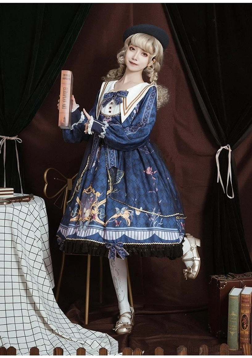 Navy sailor collar lolita dress three-quarter front view on model, holding vintage hardcover book, long puff sleeves with lace trim, detailed baroque floral print on blue fabric