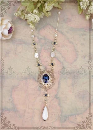 Vintage y-drop lolita necklace featuring gold filigree center setting with dark blue oval gemstone, accented with lustrous pearls, clear rhinestones and white shell pendant on retro map background