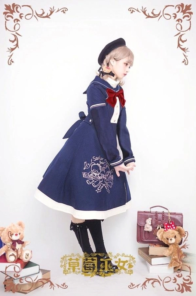 Navy blue sailor lolita overcoat with red bow tie, back three-quarter view showing rear bow decoration, bear embroidery on skirt, white contrast hem trim detail