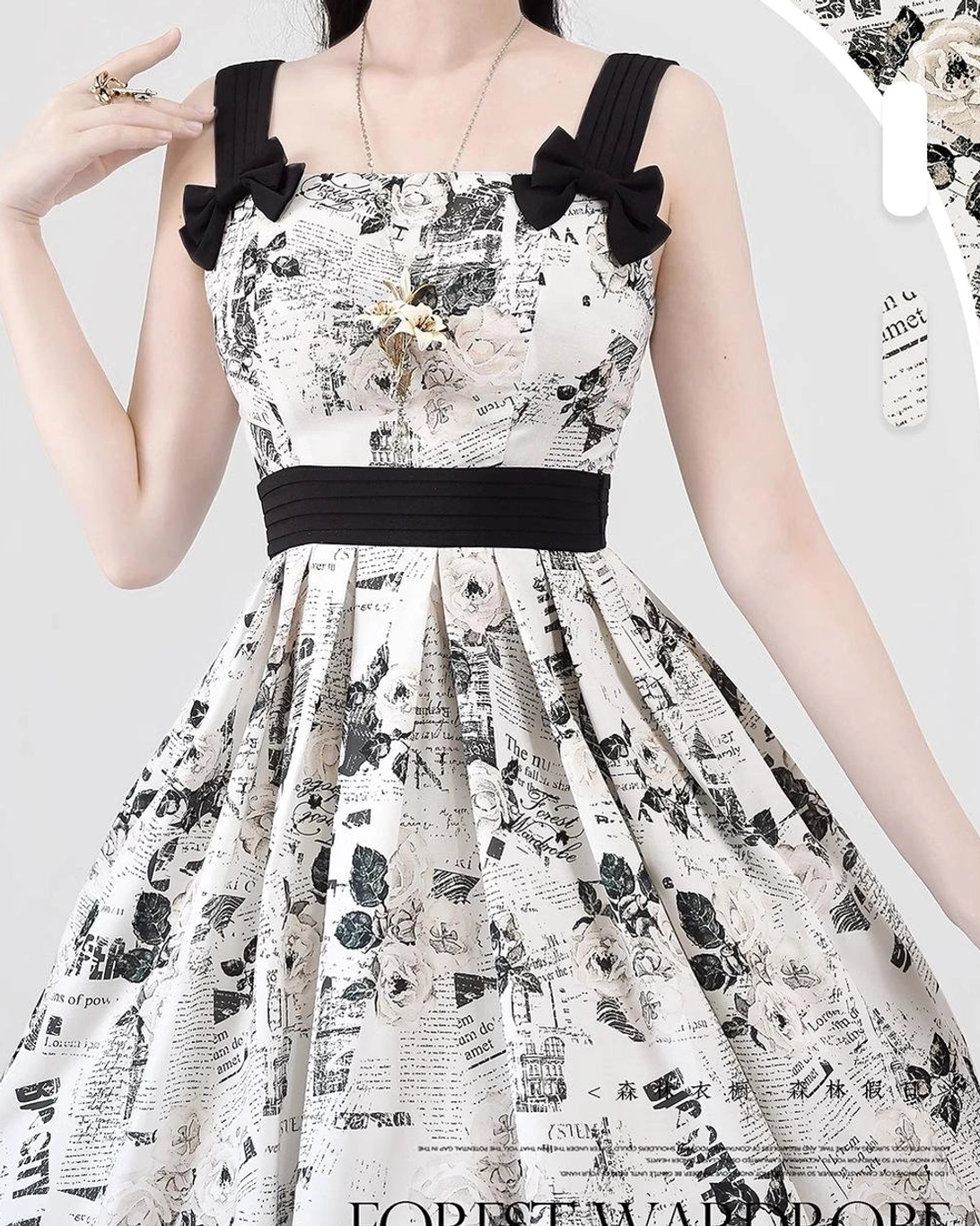 Upper body close-up detail of newspaper print lolita JSK showing black shoulder bows, wide black waist belt, vintage newspaper fabric print, and coordinating neck jewelry accessories