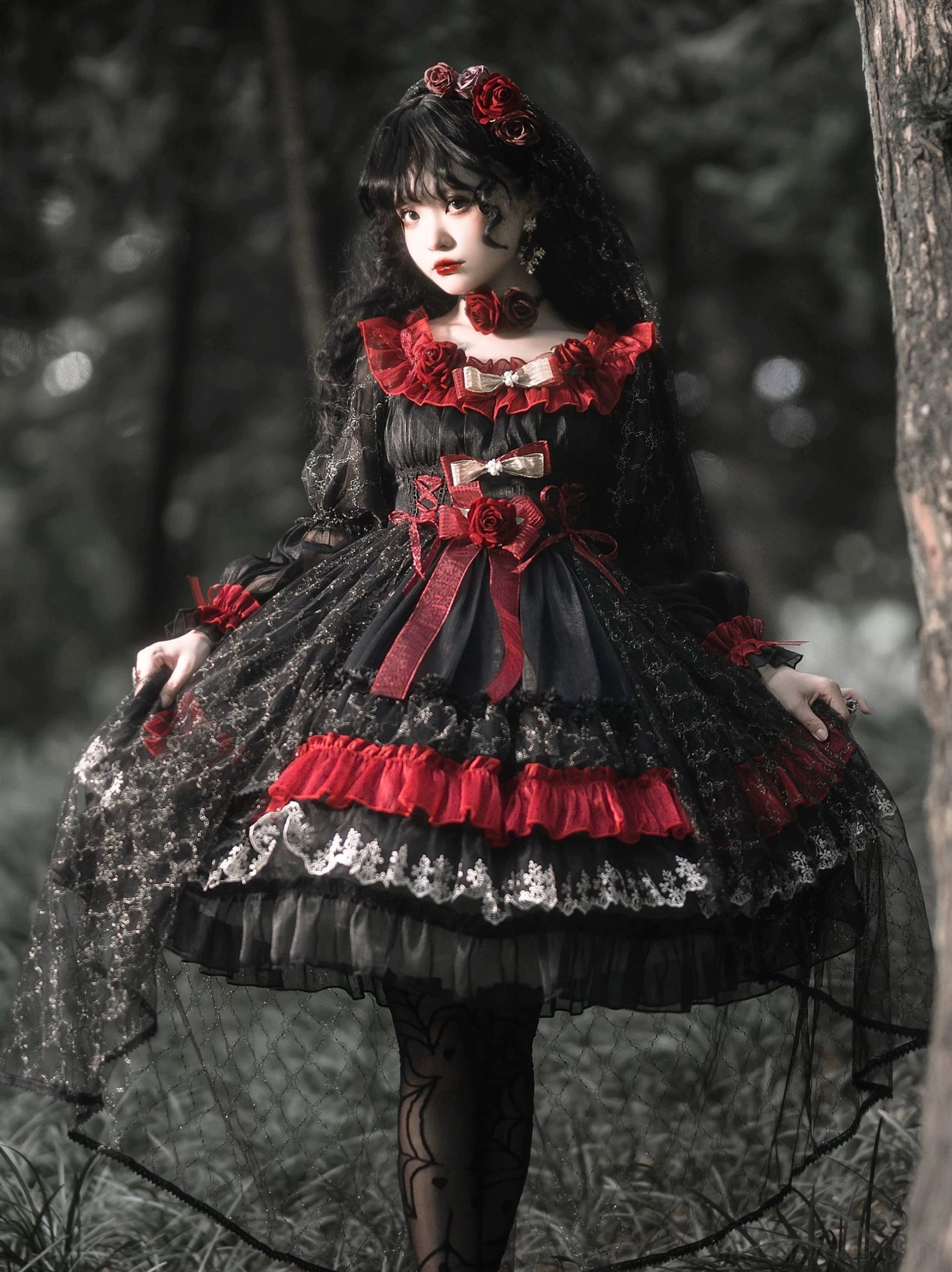 Night of Berea black and red gothic lolita OP dress full-body front view on model in dark forest outdoor setting, showcasing tiered ruffle skirt, sheer lace sleeves, and multi-layered design