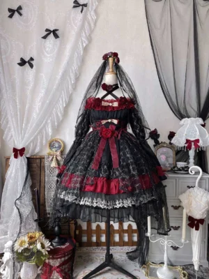 Gothic lolita OP dress on dress form display with matching red rose waist ornament and veil in vintage romantic indoor setting, showing black and red color coordination