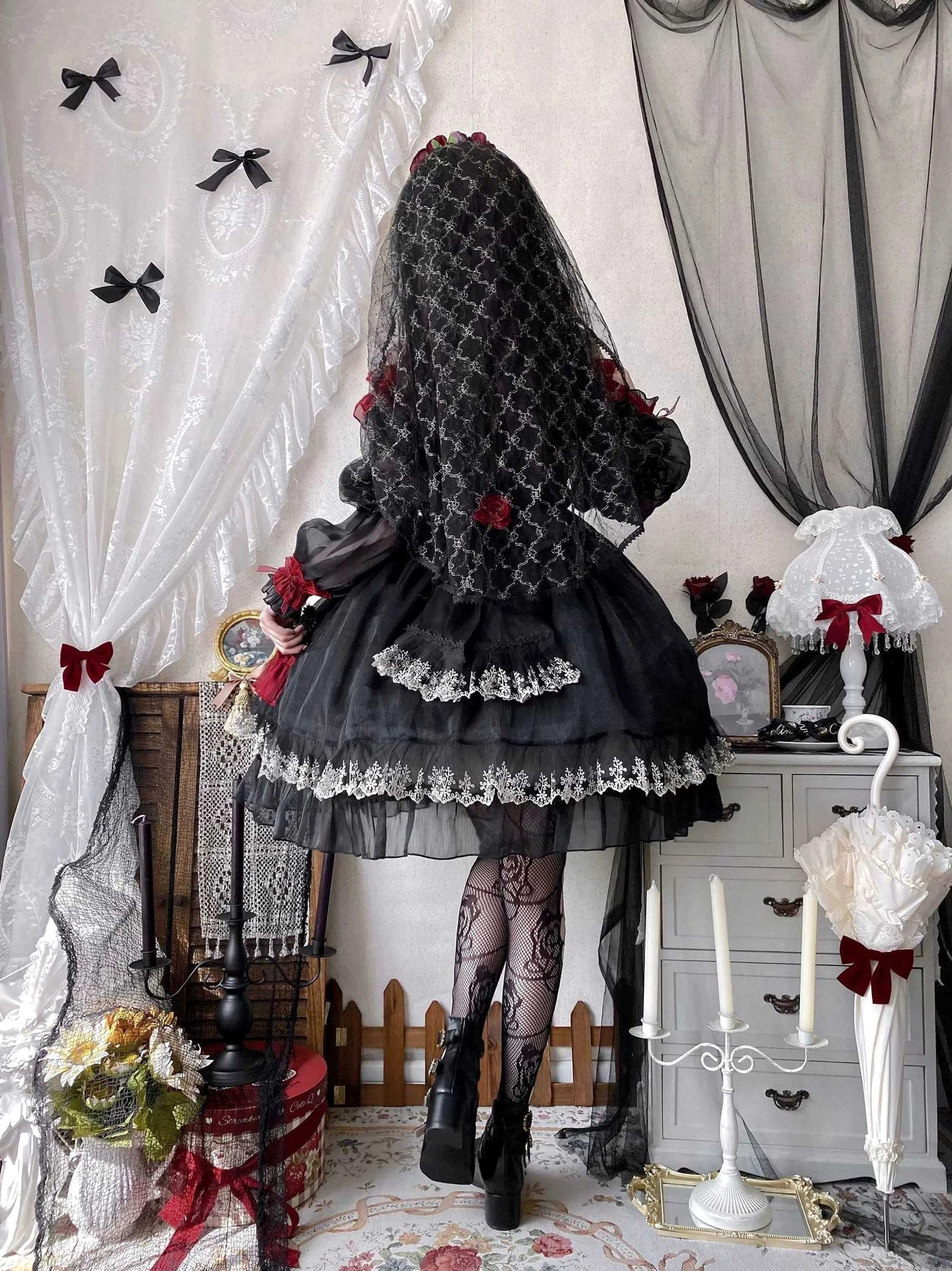 Black and red gothic lolita OP dress waist detail showing elastic shirring, ribbon bow placement, and transition to layered ruffled skirt construction