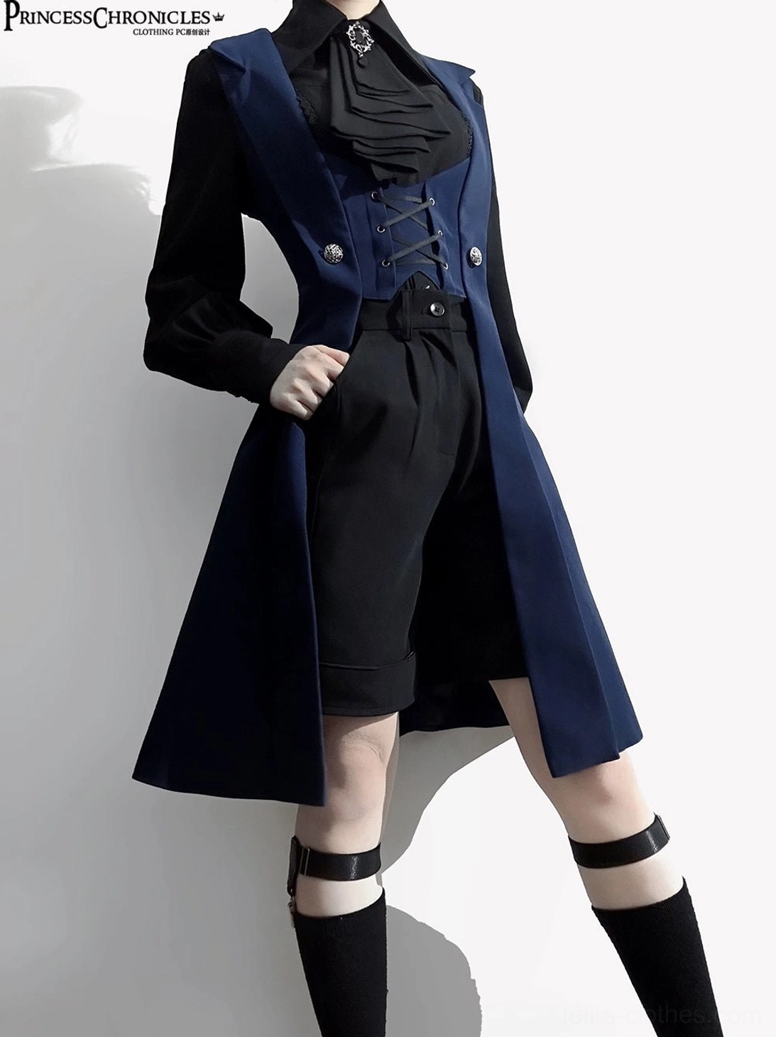 Night Prelude Gothic Ouji Lolita blue vest front three-quarter view with both hands positioned in high-waisted black shorts pockets, dual thigh harness accessories, and lace-up front details