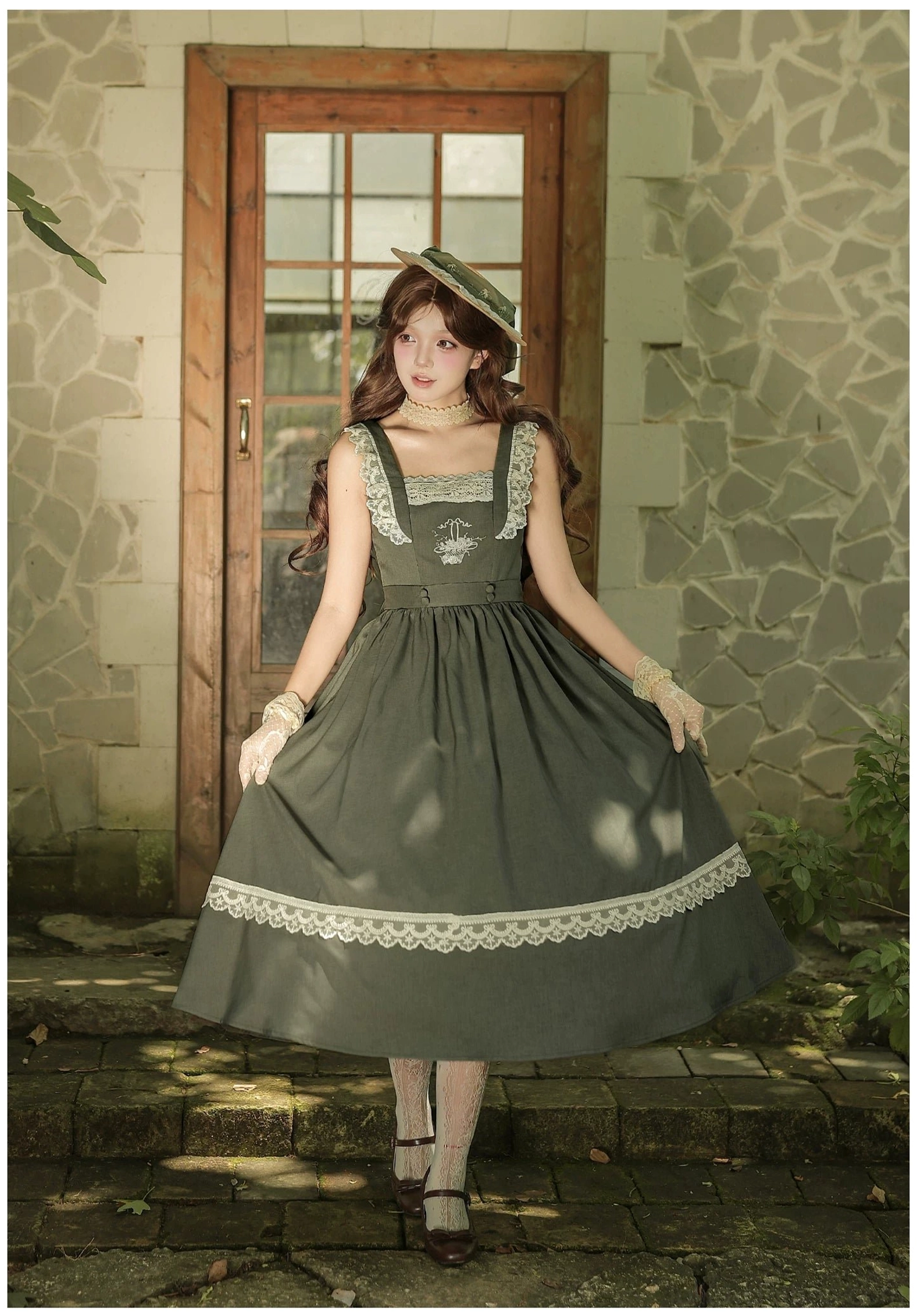 Close-up flat lay of JSK neckline and shoulder strap construction in sage green and black showing fixed shoulder strap attachment, lace ruffled neckline, and rose basket embroidery panel