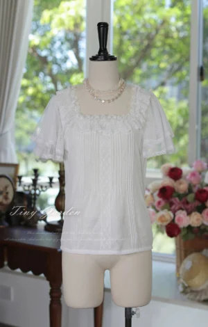 Off-white classic lolita square neck tulle blouse full-body front display shot with straight short sleeves featuring lace edge trim, pristine square neckline and decorative lace panel details against sunlit vintage backdrop