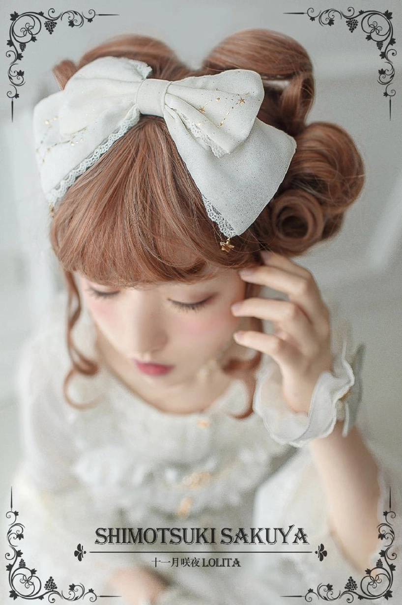 Off-white cream vintage Lolita bow KC with lace trim and star hanging charms worn by model in sweet white Lolita dress and wrist accessories