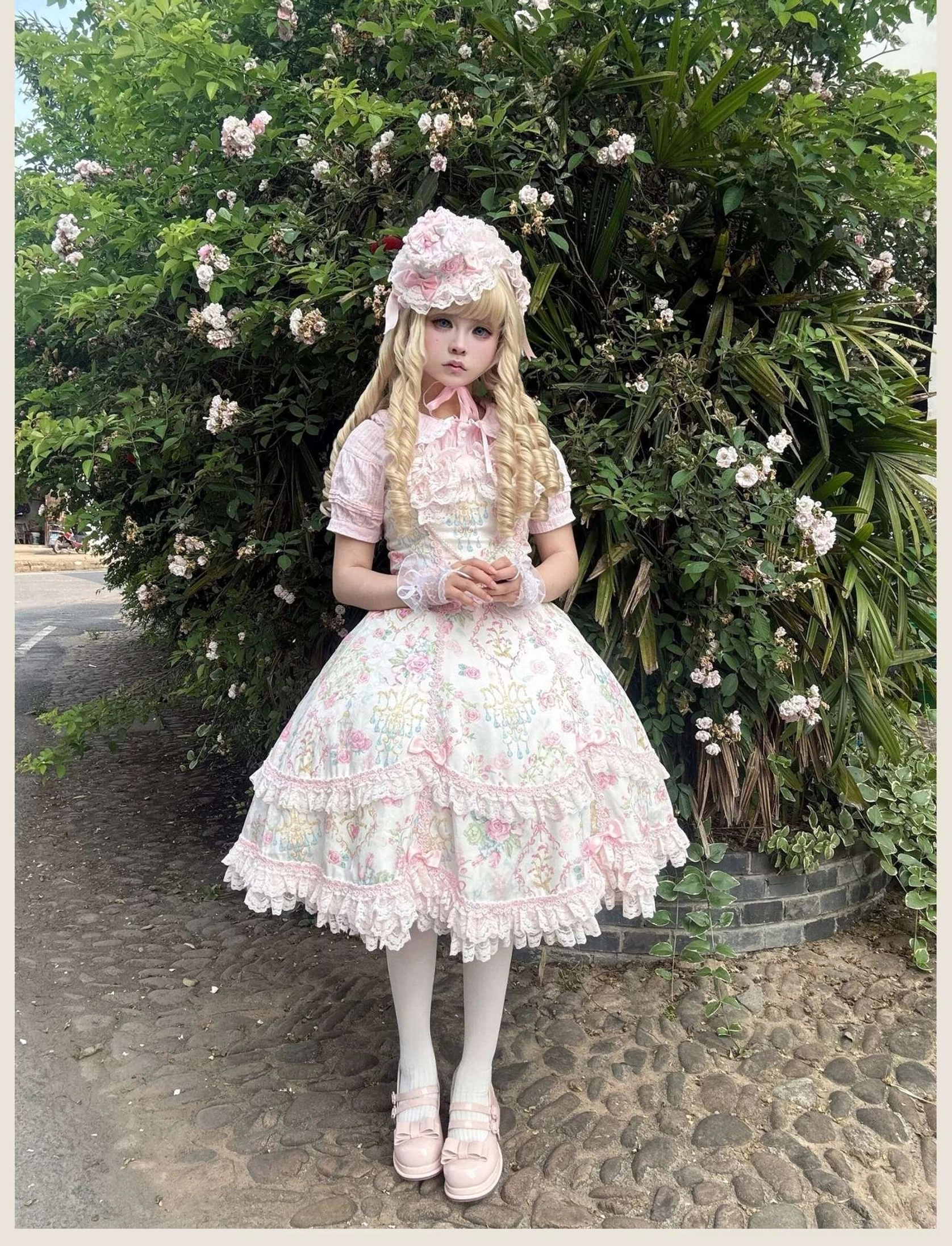 Pink floral old school Lolita JSK dress with puffed sleeves and matching headpiece on model wearing white stockings and pink round-toe shoes