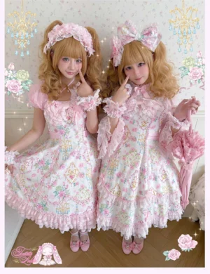 Two blonde lolita models wearing matching vintage floral print old school lolita jumper skirt dresses with pink hair bows, square necklines, ruffled trims, and coordinating flat shoes in pink-themed vintage studio setting