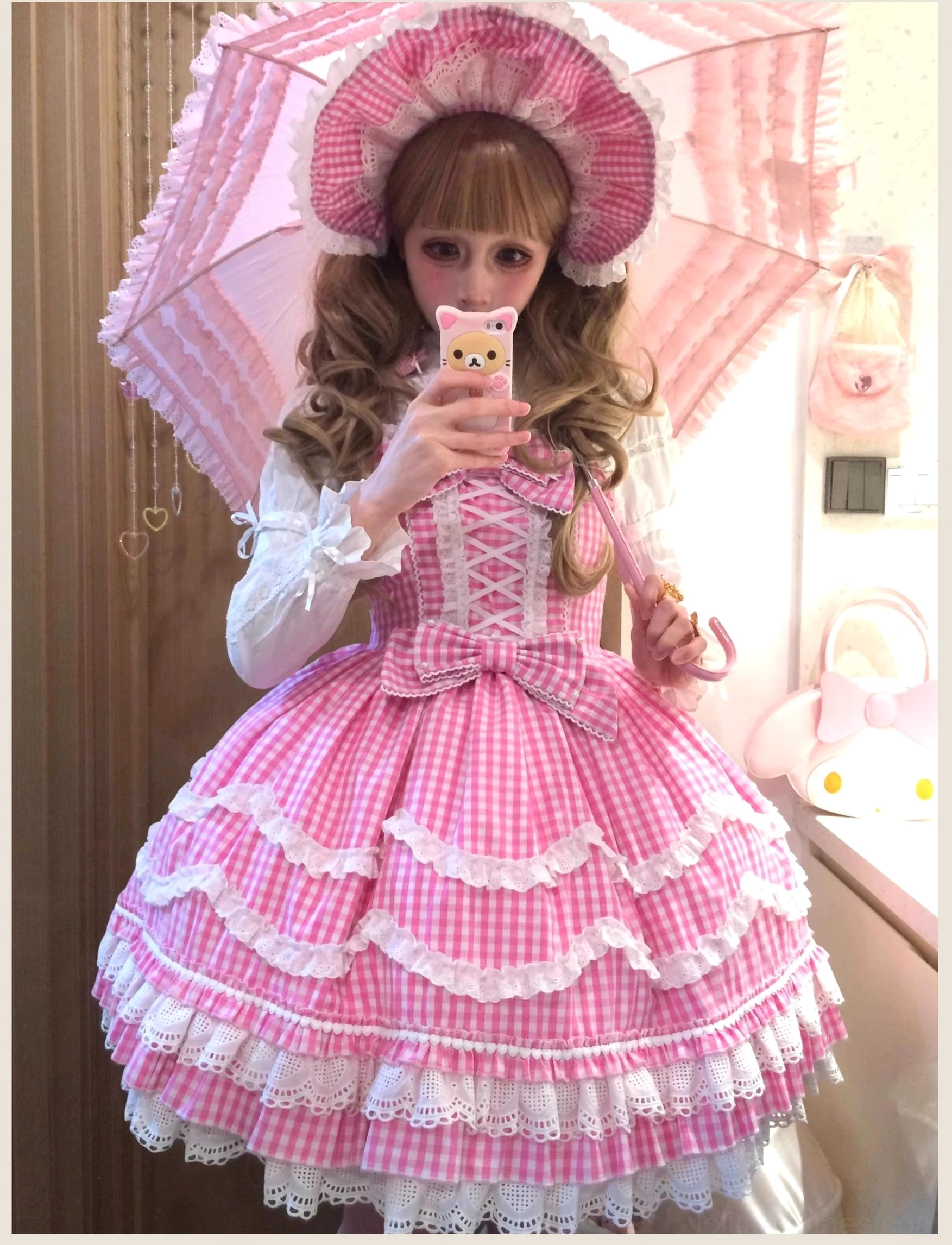 Vintage-inspired pink gingham Lolita JSK dress with petal ruffles and white lace trim, full-body front view showing structured silhouette paired with pink lace parasol and matching hair accessories