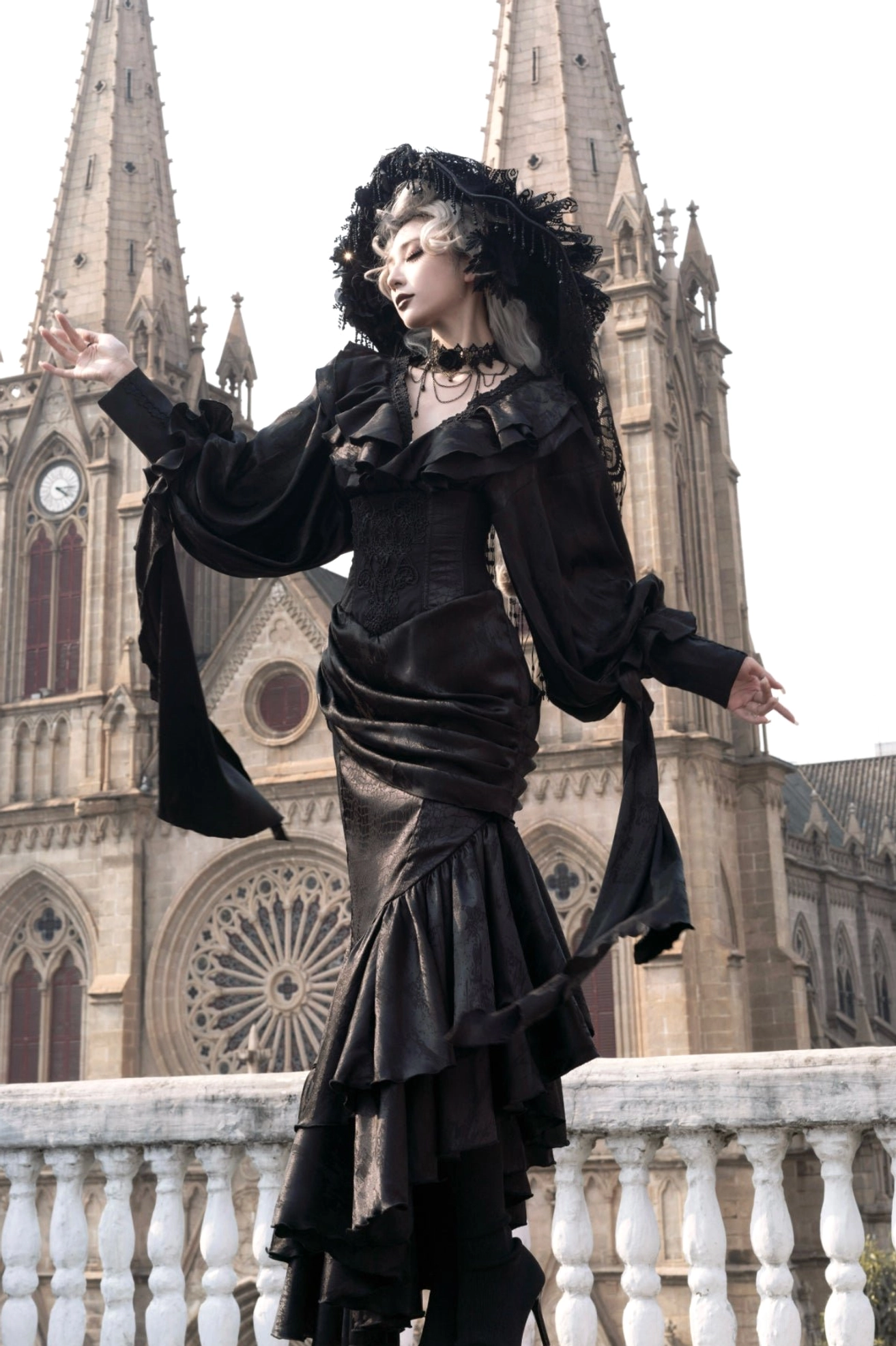 Black Oracle gothic lolita mermaid skirt worn on model at cathedral balcony with detachable sleeve sashes and puff sleeves
