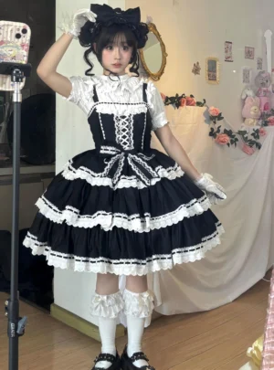 Black and white vintage old school lolita JSK jumper skirt with heart-shaped lace trim, adjustable straps, tiered ruffled skirt, front-facing full-body selfie styling with cat ear headbow