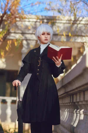 Ouji gothic long coat with detachable shoulder cape worn by silver-haired male model in European courtyard holding umbrella and book, showcasing elegant cross pendant and full-body lolita fashion silhouette