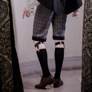 Ouji Lolita black calf socks with leg garters rear view, male model wearing checkered Ouji shorts and brown dress shoes, decorative curtain background, lower body coordinate