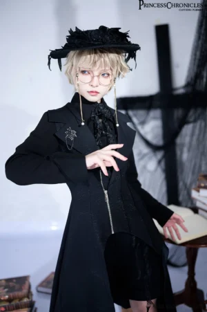 Blonde model wearing black Ouji Lolita vest with feathered hat round glasses and complete gothic coordinate set in studio setting with vintage books