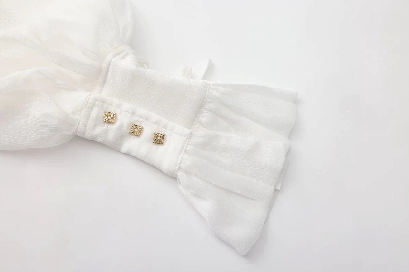 Macro close-up detail of white pirate prince ouji lolita blouse cuff strap showing three vintage gold decorative buttons and neatly stitched ruffled cuff edge, flat lay detail