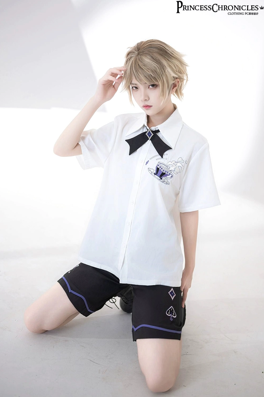 Androgynous model wearing ouji lolita embroidered short-sleeve shirt with bow tie and black socks combat boots - side kneeling pose alternative fashion