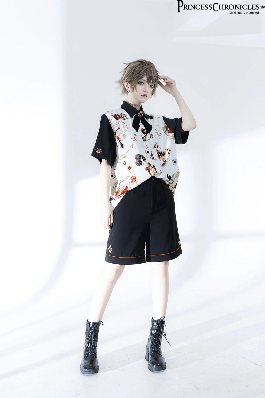 Ouji Lolita two-piece set side standing pose showing printed shirt design details and black shorts with orange lace trim, model with hand to head gesture