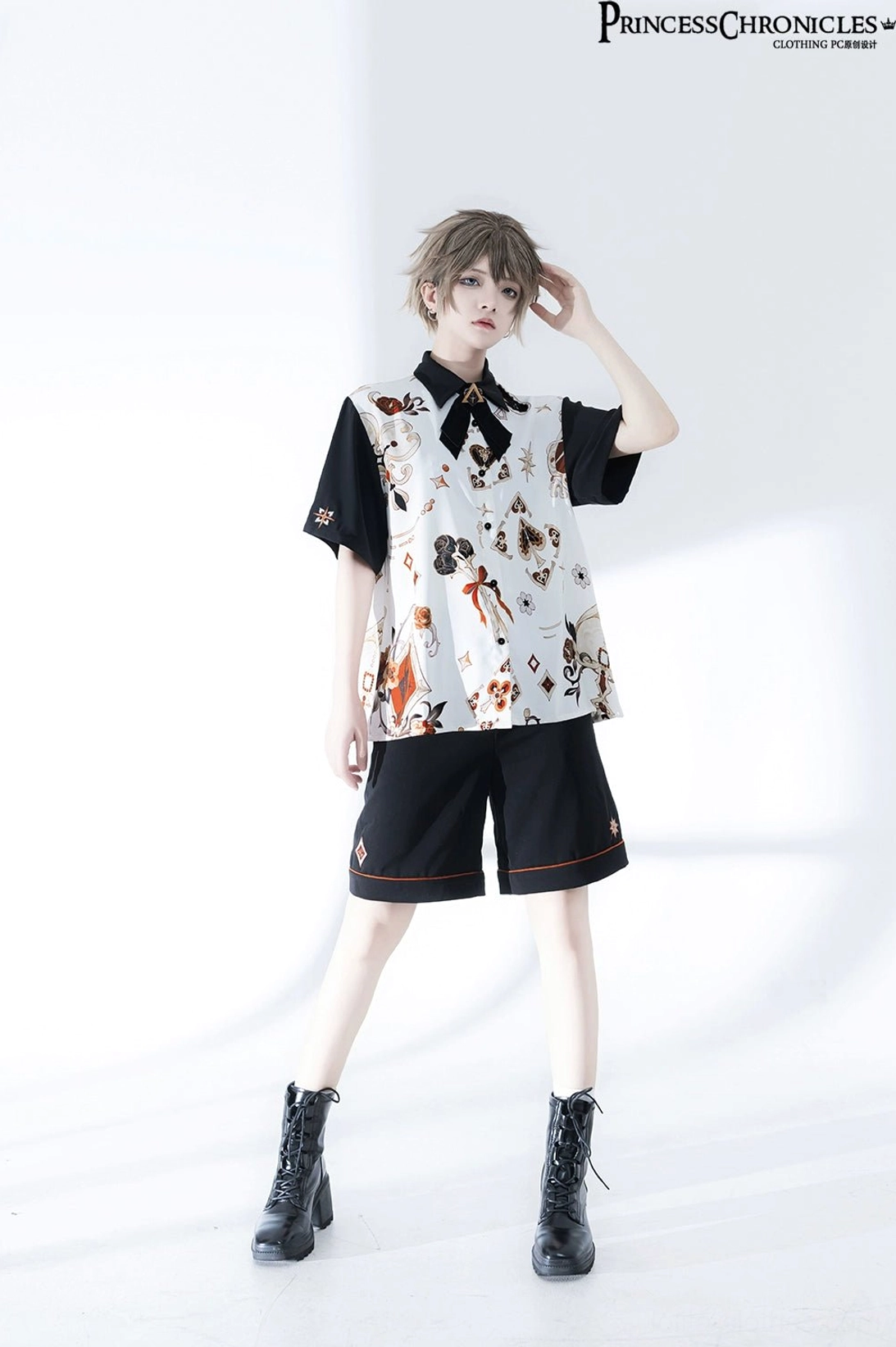 Ouji Lolita two-piece outfit side profile showing back printed motifs, worn with black combat boots by androgynous male model in white studio