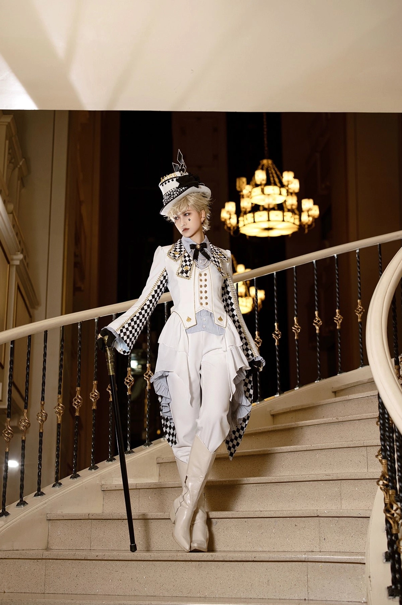 Complete ouji Lolita aristocrat prince ensemble full-length side view blonde model checkerboard sleeve trim tall top hat walking cane vintage chandelier background formal