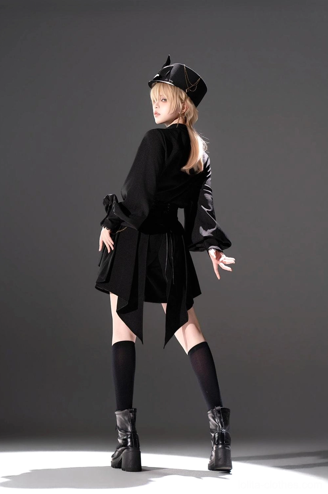 Ouji Lolita black military set side back three-quarter view showing asymmetric high-low hem shorts with platform boots and decorative shoulder brooch detail