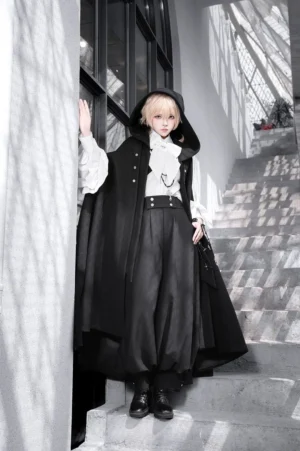 Ouji lolita ensemble three-quarter side view model wearing hooded cape with waist belt and black leather shoes at indoor staircase