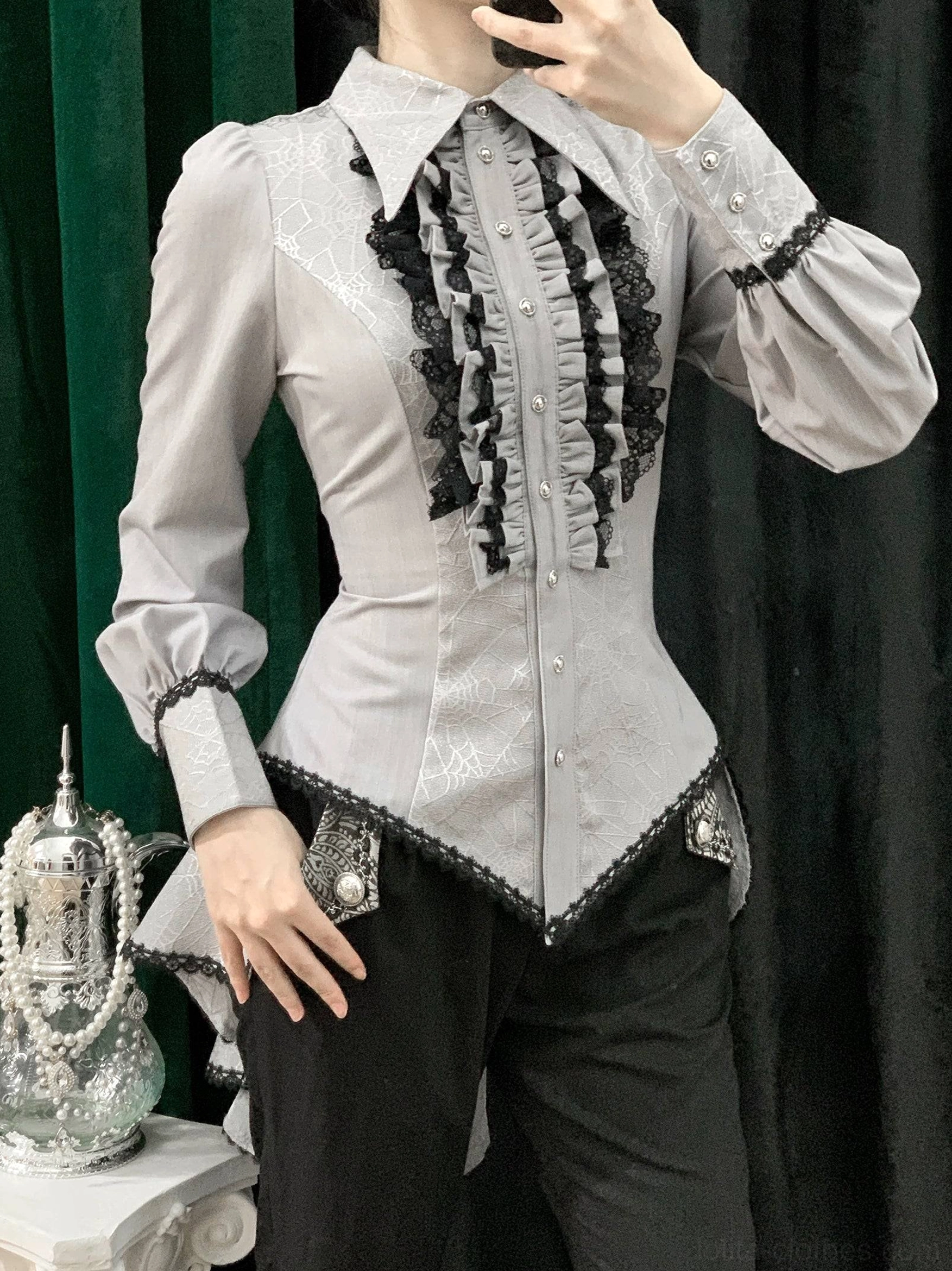Light gray gothic Ouji lolita spiderweb shirt side view on model showing black lace ruffle front black cuff trim hip patches and spiderweb jacquard texture