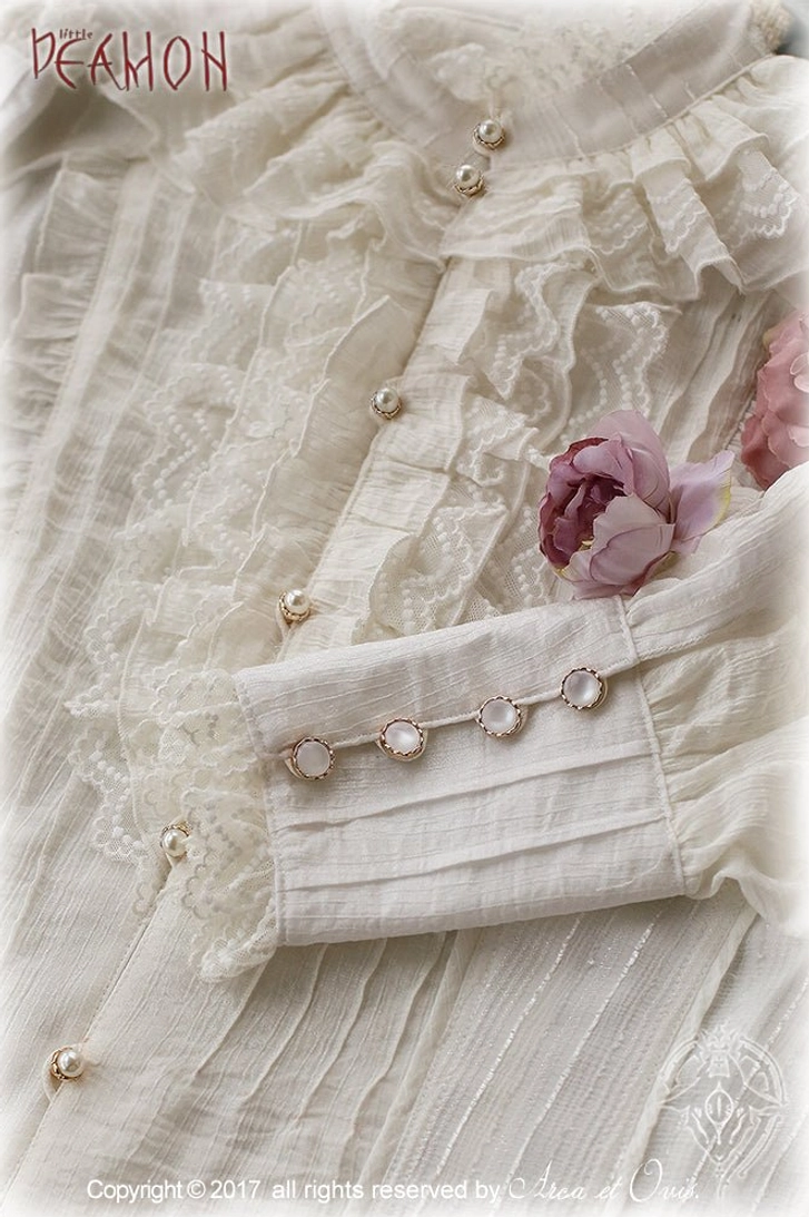 Close-up detail of white Ouji ruffled lolita blouse showing pearl buttons, ruffled lace collar, wrinkled crinkle fabric texture and lace-trimmed cuffs with decorative buttons