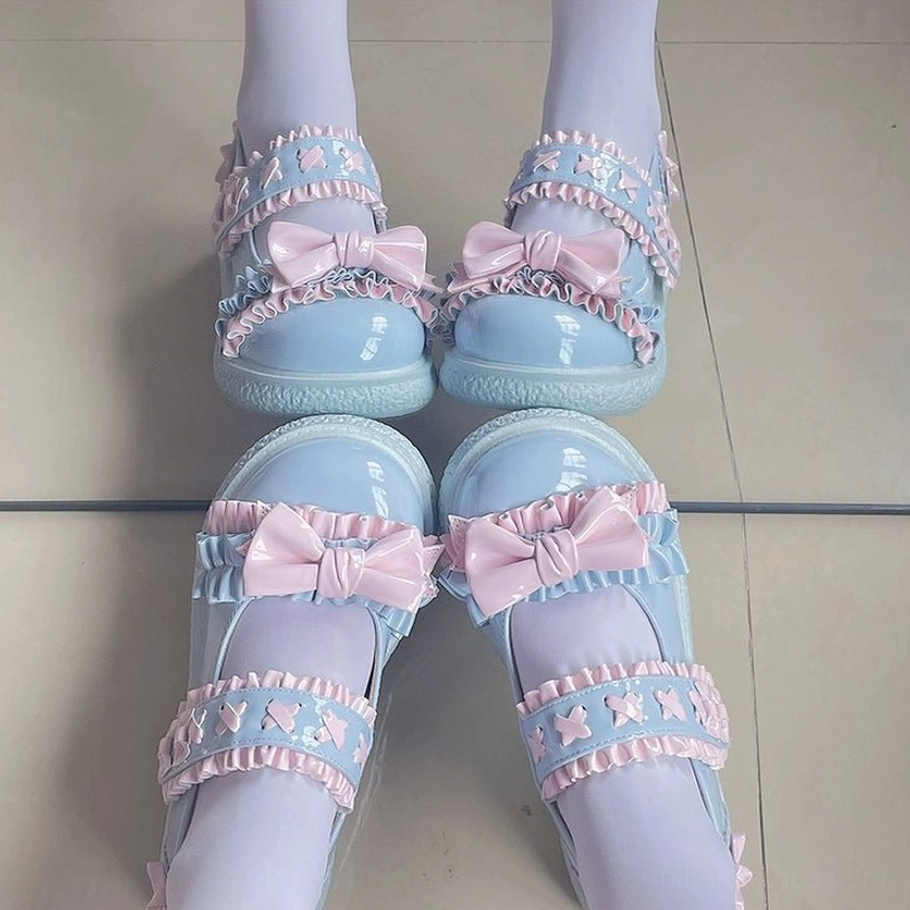 Paint white Lolita shoes close-up showing glossy patent leather finish, decorative butterfly bows, ruffled straps and artistic accent styling in monochrome palette