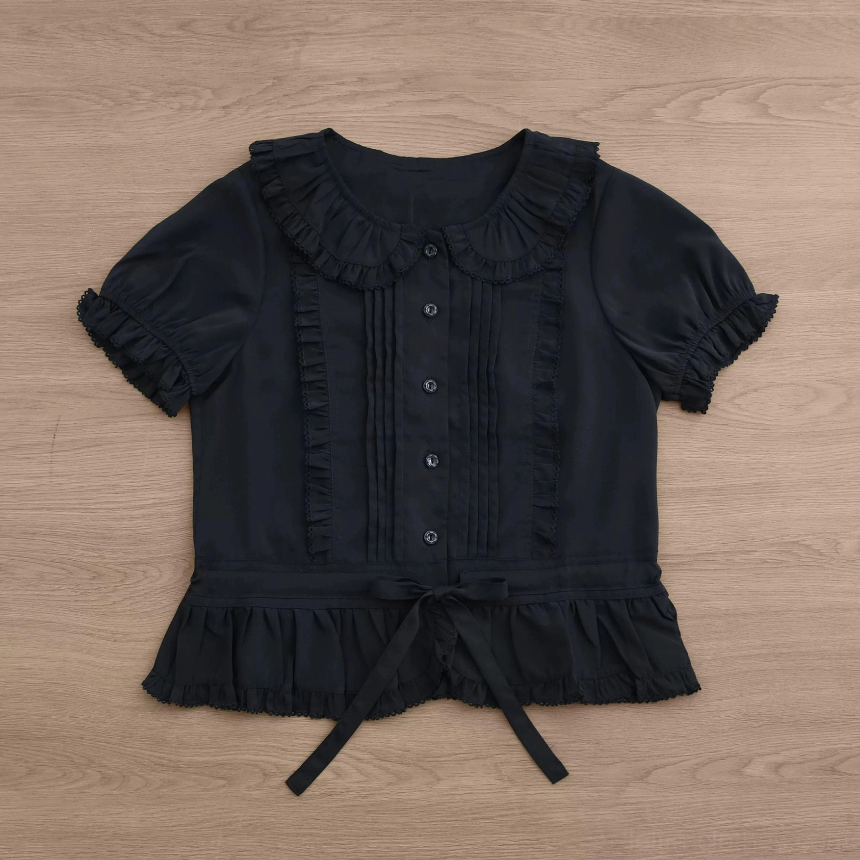 Sweet Lolita blouse in pale pink or rose showing ruffled collar, front pintuck details, short puff sleeves, button placket, drawstring waist, and hem flounce
