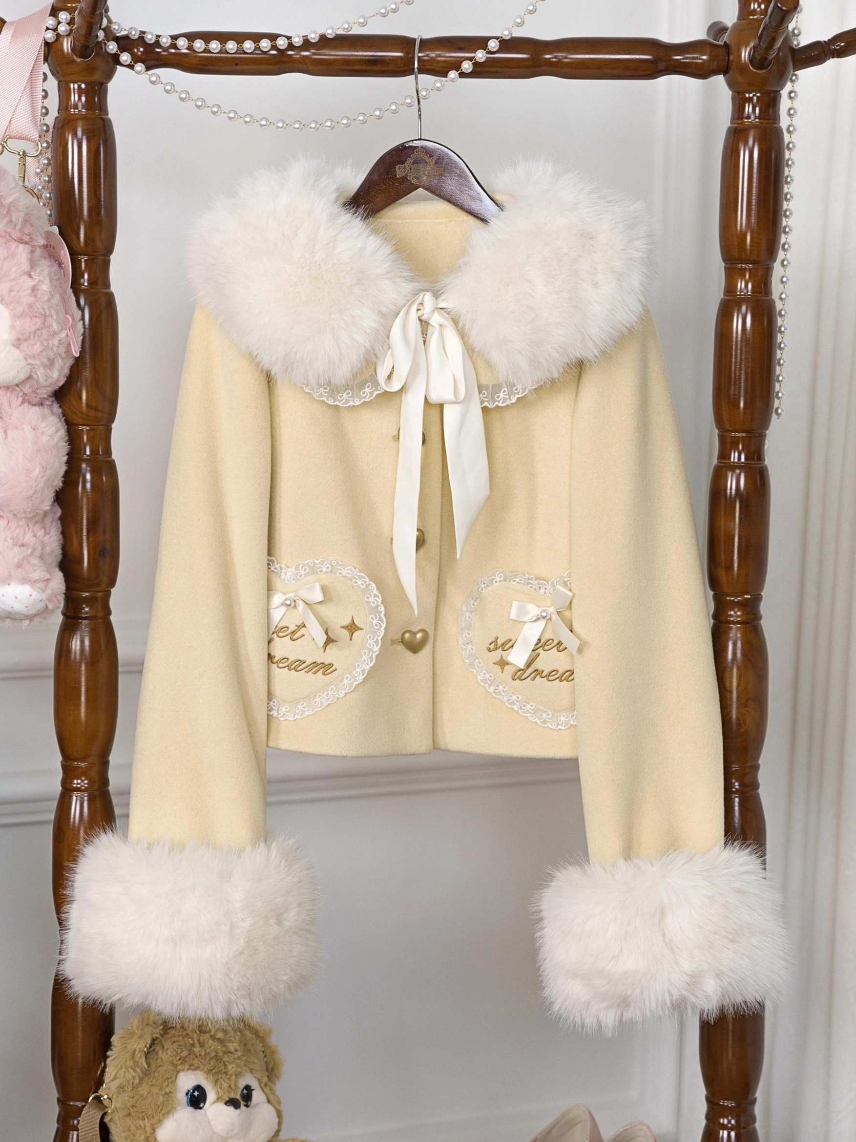 Light yellow pale sweet lolita coat with heart-shaped embroidered pockets and fluffy faux fur collar and cuffs, shown on vintage display with lolita aesthetic